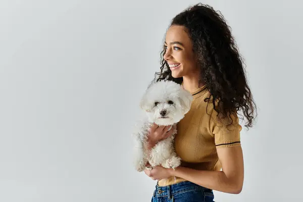 Young woman tenderly holds and cuddles a white bichon frise dog in her hands. — Stock Photo