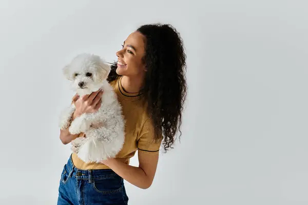 Una donna culla delicatamente un cane bianco Bichon Frise tra le braccia. — Foto stock