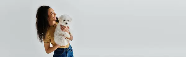 Woman tenderly holds her bichon frise in her arms. — Stock Photo
