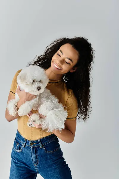 Mujer acunando suavemente su mullido bichon blanco frise en sus manos. - foto de stock