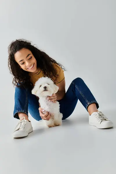 A woman tenderly kneeling with a white bichon frise in a peaceful moment. — Stock Photo