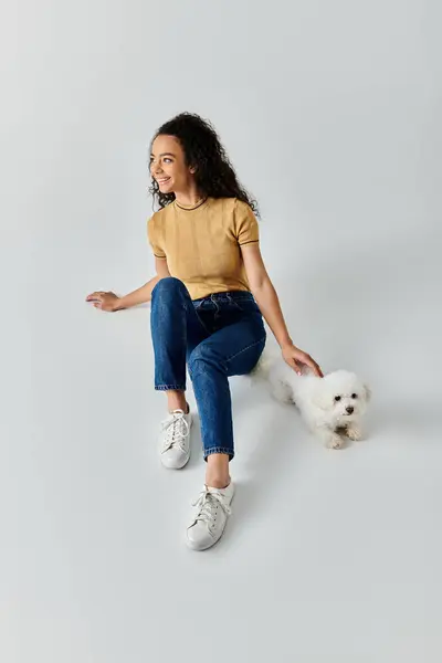A woman and her bichon frise sitting on the ground. — Stock Photo