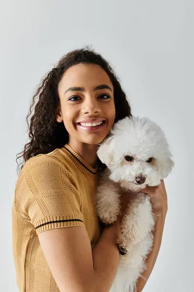 A woman peacefully holds a white dog in her arms. — Stock Photo