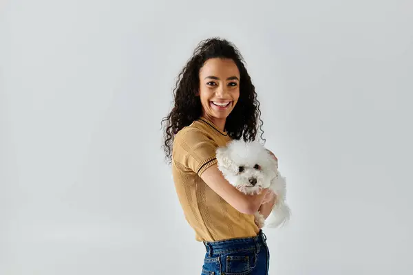 A young woman lovingly holds her white Bichon Frise dog in her arms. — Stock Photo