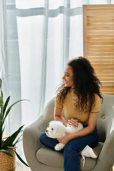 Woman sitting in chair, tenderly holding white dog. — Stock Photo