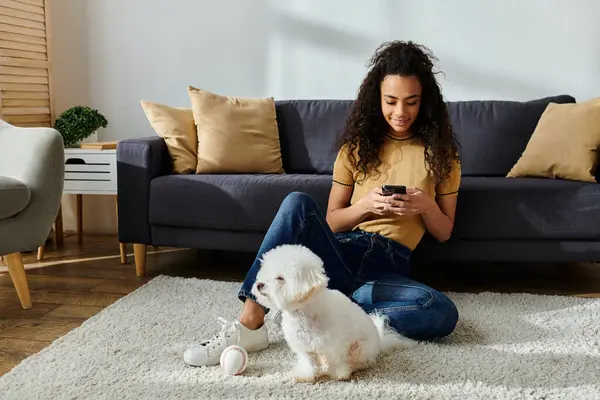 Donna seduta sul pavimento, assorbita nel cellulare, con cane. — Foto stock
