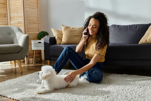 Woman with bichon frise chats on cell phone while seated. — Stock Photo