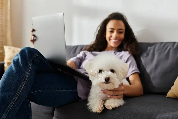 Young woman with laptop and bichon frise on couch. — Stock Photo