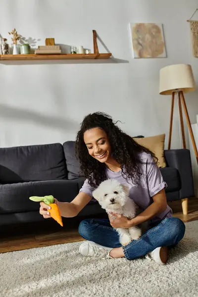 Woman happily seated, interacting with fluffy bichon frise dog. — Stock Photo