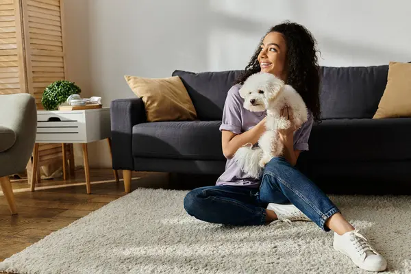 Woman sitting on floor, tenderly holding white dog. — Stock Photo