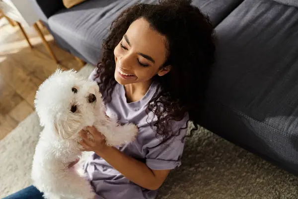 A woman sitting on the floor holding her white dog, expressing peace and companionship. — Stock Photo