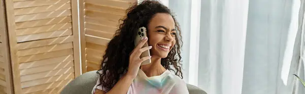 Woman sitting, chatting animatedly on cell phone in comfy chair. — Stock Photo