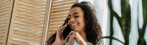 A woman speaking on a cell phone by the window. — Stock Photo