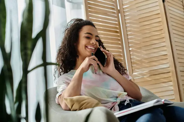 A woman seated on a couch conversing on a cell phone. — Stock Photo