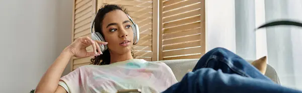 Woman sitting on couch, using mobile phone, headphones. — Stock Photo