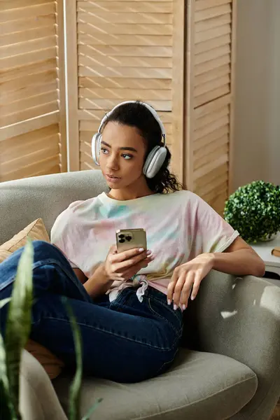 A woman in headphones enjoys music on a couch. — Stock Photo