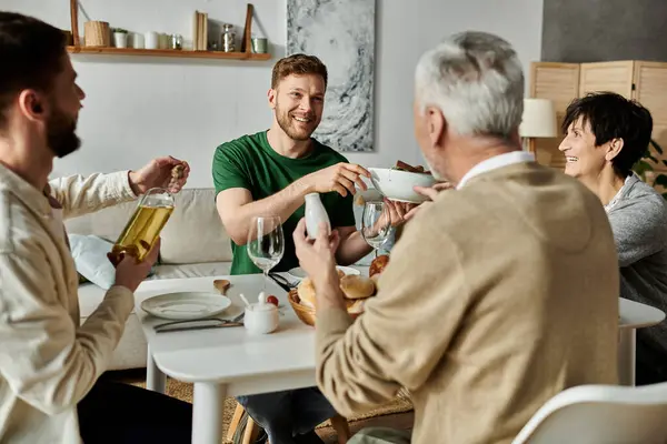 A gay couple sits at a table with parents, sharing a meal and enjoying each others company. — Stock Photo