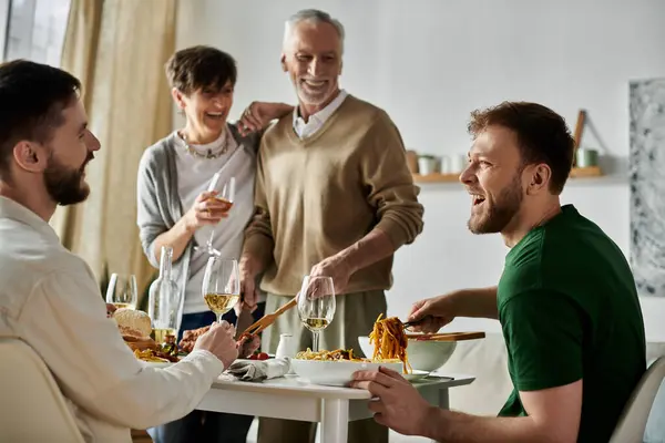 A gay couple enjoys a meal with parents at home. — стоковое фото
