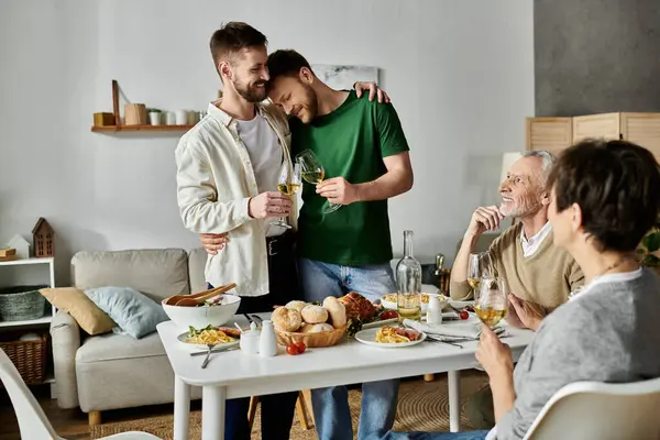 A gay couple stands together, arms around each other, while introducing their partner to their family during a celebratory dinner at home. — Stock Photo