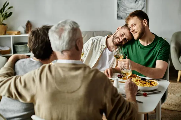 A gay couple sits at a dining table with their family, enjoying a meal and conversation. — Stock Photo