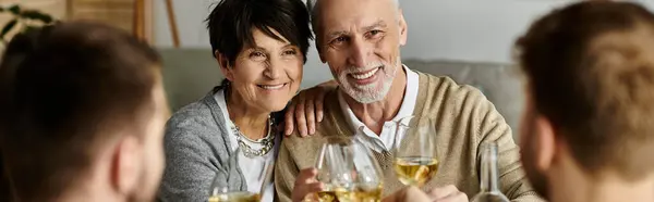 Les parents joyeux partagent le repas avec leur fils et son partenaire lors d'un dîner confortable à la maison. — Photo de stock