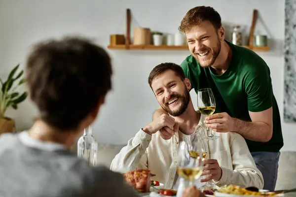 A gay couple enjoys a meal with their family. — стоковое фото