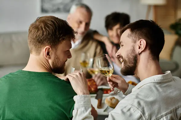 A gay couple enjoys a dinner with parents at home, sharing a toast. — Stock Photo