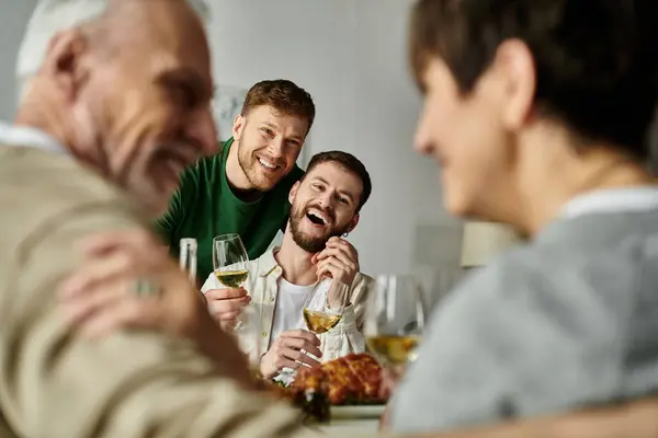 Un couple gay profite d'un repas avec les parents à la maison. — Photo de stock