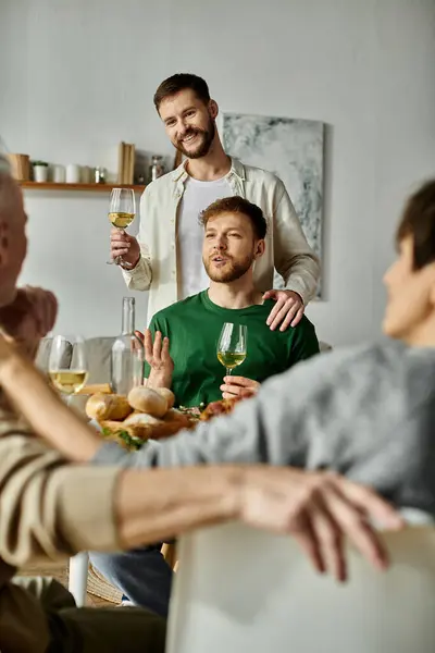 Ein schwules Paar genießt eine Mahlzeit mit den Eltern zu Hause und hebt ein Glas in einem herzerwärmenden Moment der Zweisamkeit. — Stockfoto