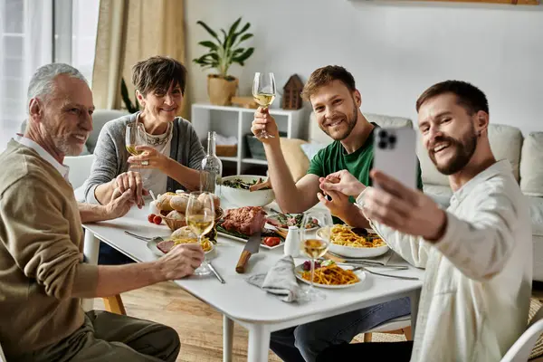 Un couple gay et ses parents partagent un repas et sourient à la maison. — Photo de stock