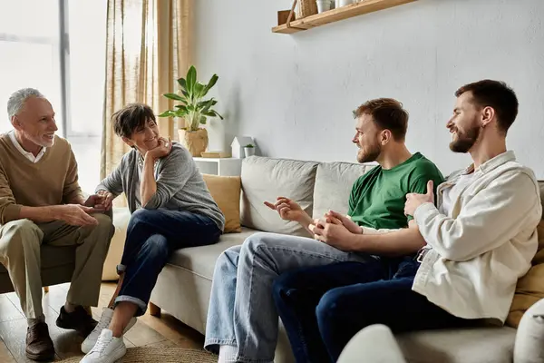 Um casal gay se senta em um sofá com os pais, desfrutando de uma conversa relaxada. — Fotografia de Stock