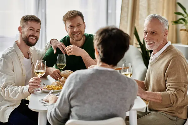 A gay couple enjoys a dinner with parents at home, sharing laughter and wine. — стоковое фото