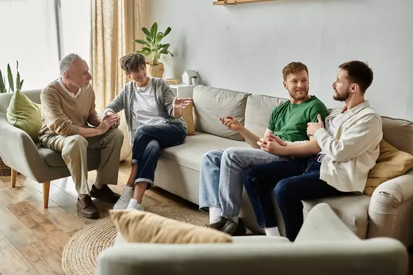 A gay couple sits on a couch while parents sit nearby, all engaging in conversation. — стоковое фото