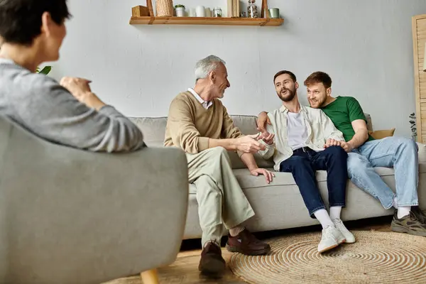 A gay couple sits with parents on a couch, laughing and sharing stories. — Stock Photo