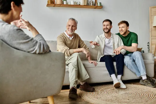 A gay couple sits on a couch with parents, smiling and talking. — Stock Photo