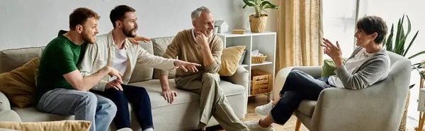 A gay couple sits on a couch with parents, sharing a conversation in a warm and inviting home setting. — Stock Photo