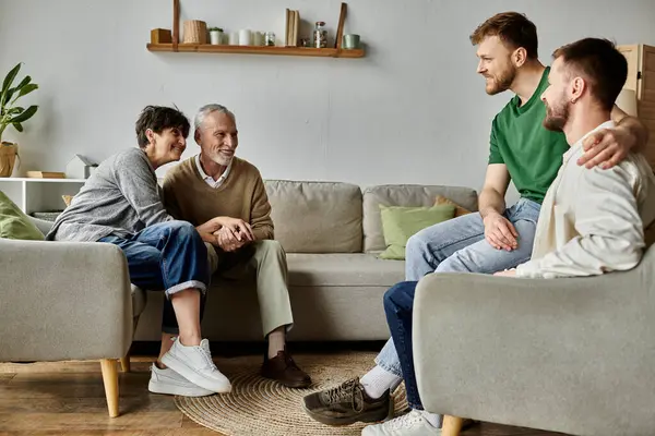 Un couple gay s'assoit sur un canapé avec ses parents, partageant un moment de convivialité. — Photo de stock