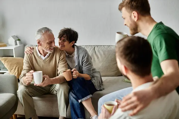 A gay couple sits on a couch with parents, sharing a warm moment together. — Stock Photo