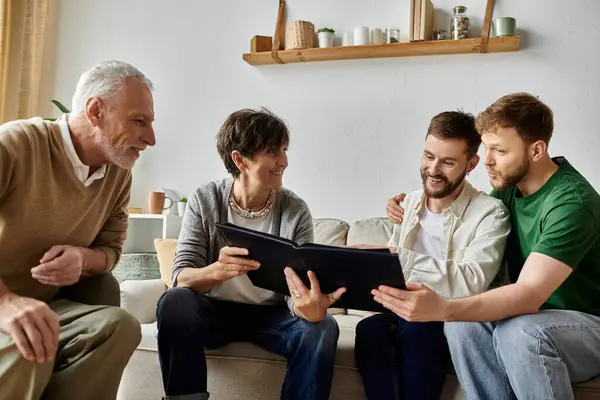 A gay couple sits on a couch with parents, sharing photos from a photo album. — Stock Photo