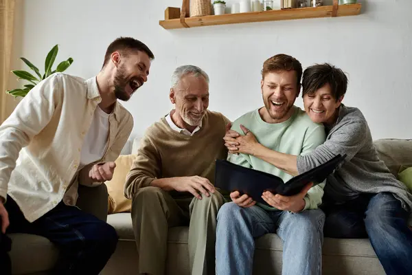 A gay couple shares a laugh with parents while looking at an old photo album. — Stock Photo
