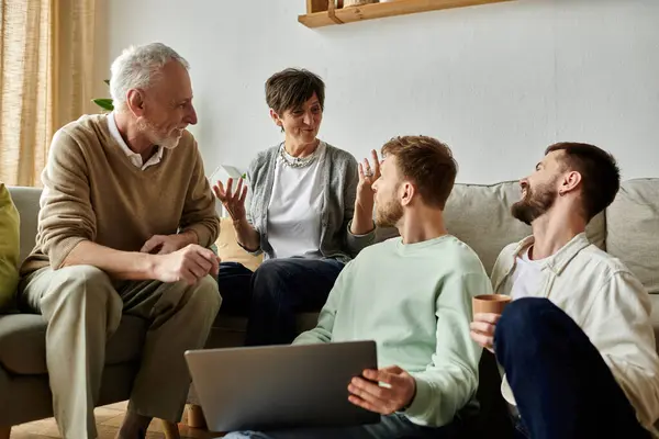 Una pareja gay y sus padres comparten una conversación cálida y atractiva en su sala de estar. - foto de stock