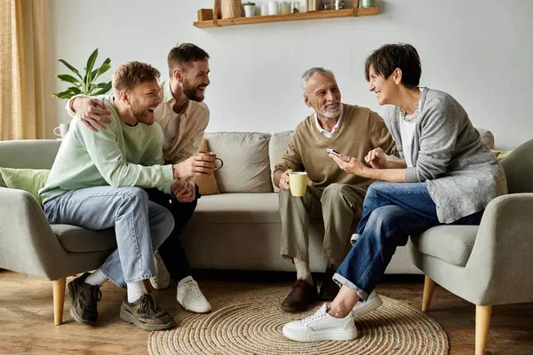 A gay couple sits on a couch with parents, laughing and enjoying each others company. — Stock Photo
