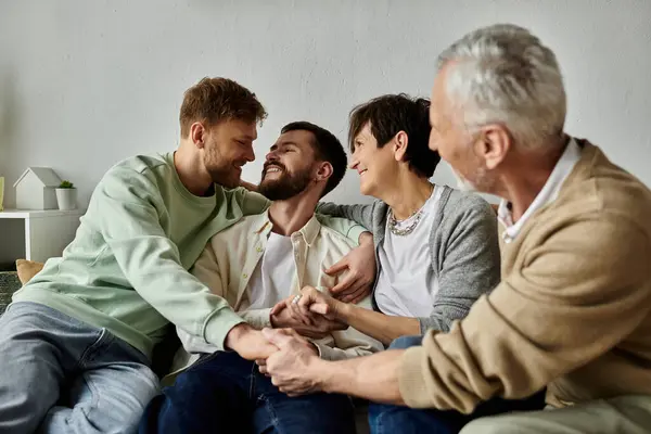 A gay couple sits on a couch with parents, smiling and holding hands. — Stock Photo