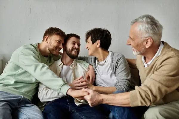 A gay couple sits on a couch with parents, holding hands and smiling warmly. — Stock Photo