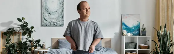 Um homem com inclusividade está em sua casa, olhando atentamente para o horizonte, vestido com uma camisa cinza. — Fotografia de Stock