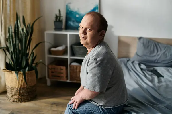 Um homem com inclusividade senta-se na beira de uma cama em um quarto. — Fotografia de Stock