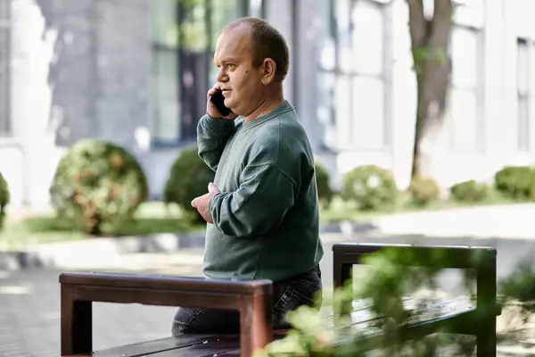 Ein inklusiver Mann telefoniert, während er neben einer Bank steht, gebadet im warmen Licht eines sonnigen Tages. — Stockfoto