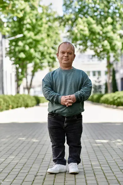 A man with inclusivity stands confidently on a brick walkway, surrounded by greenery. — Stock Photo