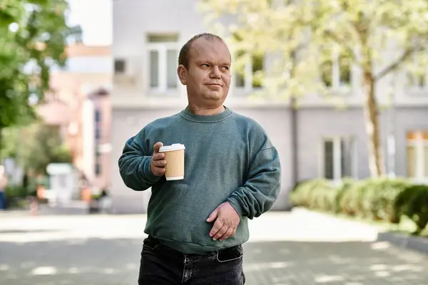 Человек с инклюзивностью идет по улице, держа чашку кофе. — Stock Photo