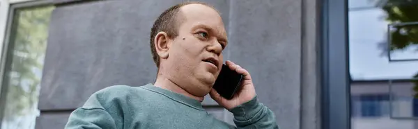 A man with inclusivity speaks on the phone outside his home. — Stock Photo